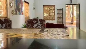 A spacious room with a polished floor, a wooden ceiling, and a large window.