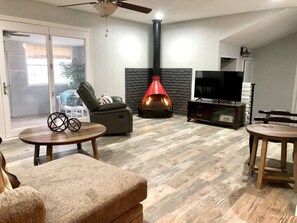 A living room with a fireplace, a television, and a ceiling fan.