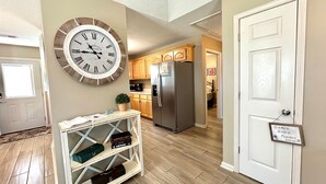Una cocina con armarios de madera, un refrigerador de acero inoxidable y un reloj de pared.