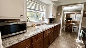 A modern kitchen with a built-in microwave, stainless steel sink, and wooden cabinets.