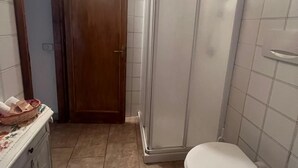 Une salle de bain comprenant un espace douche, des toilettes et un lavabo.