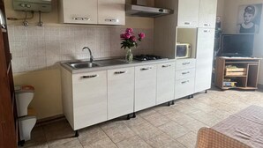 Une cuisine avec des meubles blancs, un évier et une cuisinière. Un vase rempli de fleurs est posé sur le comptoir.