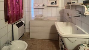 Une salle de bain avec un lavabo blanc, un bidet, un miroir et un espace douche.