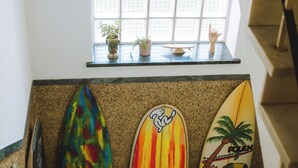 A staircase with a handrail, a window with a view of the outside, and three surfboards leaning against the wall. - Lisbon Soul Surf Camp (Cascais)