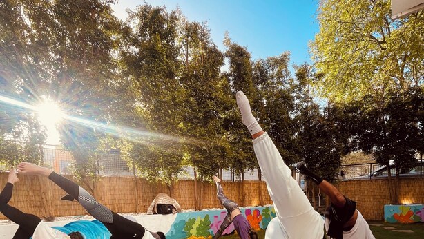 A group of people practicing yoga outdoors on mats and blankets. - Lisbon Soul Surf Camp (Cascais)