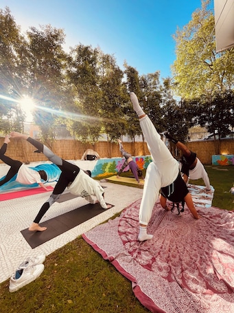 People practicing yoga outdoors on mats.. Lisbon Soul Surf Camp