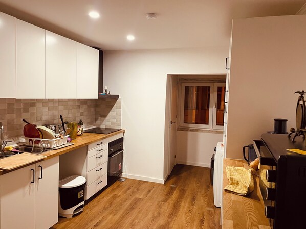 A compact kitchen with white cabinets, a wooden countertop, and a window.