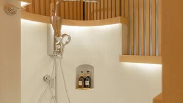 Un baño moderno con cabina de ducha de vidrio, dispensador de jabón empotrado y diseño de paneles de madera.