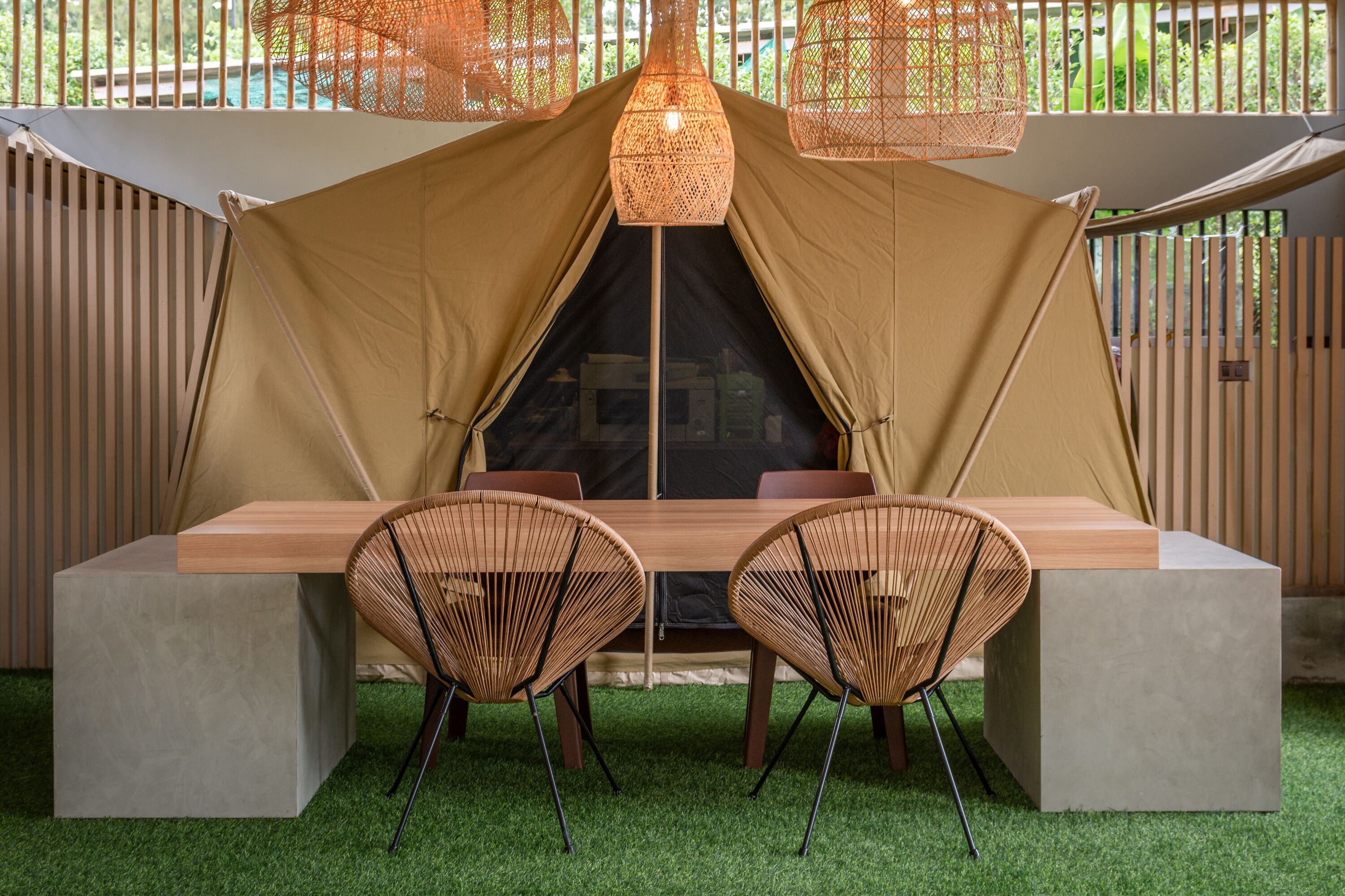 Una carpa con una mesa y sillas, rodeada por una valla de madera y follaje.