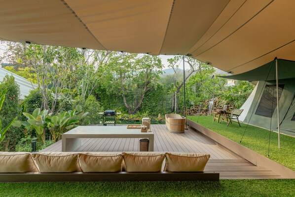An outdoor deck with a seating area, a wooden table, and a large water feature.