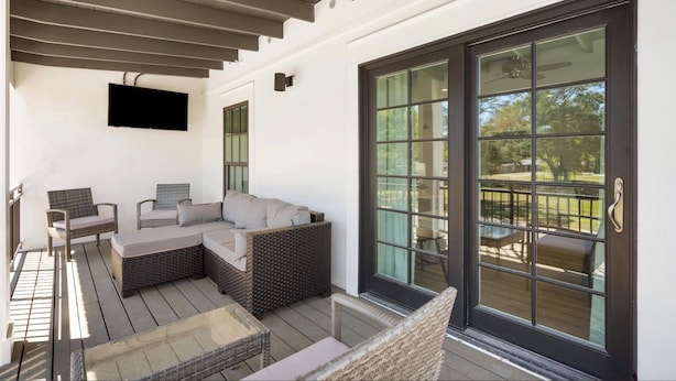 A covered outdoor seating area with wicker furniture and a large sliding glass door. - Amazing Heron Loft in Gulf Shores entertainment district (Gulf Shores)