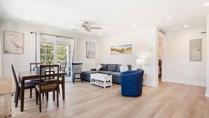 A spacious living room with a dining area, a sofa, and a blue armchair. - Amazing Heron Loft in Gulf Shores entertainment district (Gulf Shores)