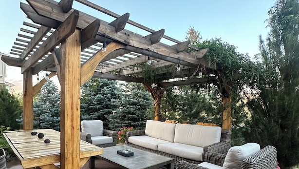 Un espace extérieur aménagé en terrasse, avec une pergola en bois, un canapé, une table et une table basse.