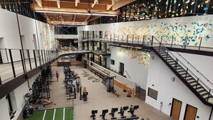 Une salle de sport à plusieurs niveaux, dotée de divers équipements d’exercice, d’un espace recouvert de gazon synthétique et d’un escalier.