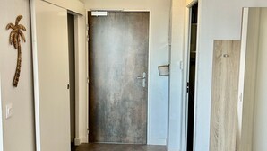 Ein Flur mit einer Leuchte, einer Tür mit strukturierter Oberfläche und einem an der Wand montierten Lichtschalter.