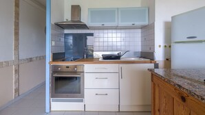 A kitchen with white cabinets, a stainless steel oven, a microwave, and a wooden countertop. - Le Petra Paoli - Front de mer -  Appt climatisé avec piscine (L'Île-Rousse)