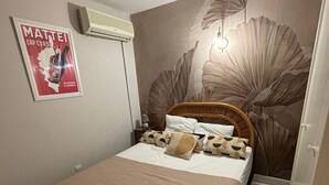 Une chambre avec un lit, une affiche, un climatiseur fixé au mur et une fresque murale à motifs floraux.