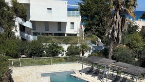 Une piscine dotée d’une terrasse carrelée, entourée d’une clôture blanche et ombragée par des parasols.