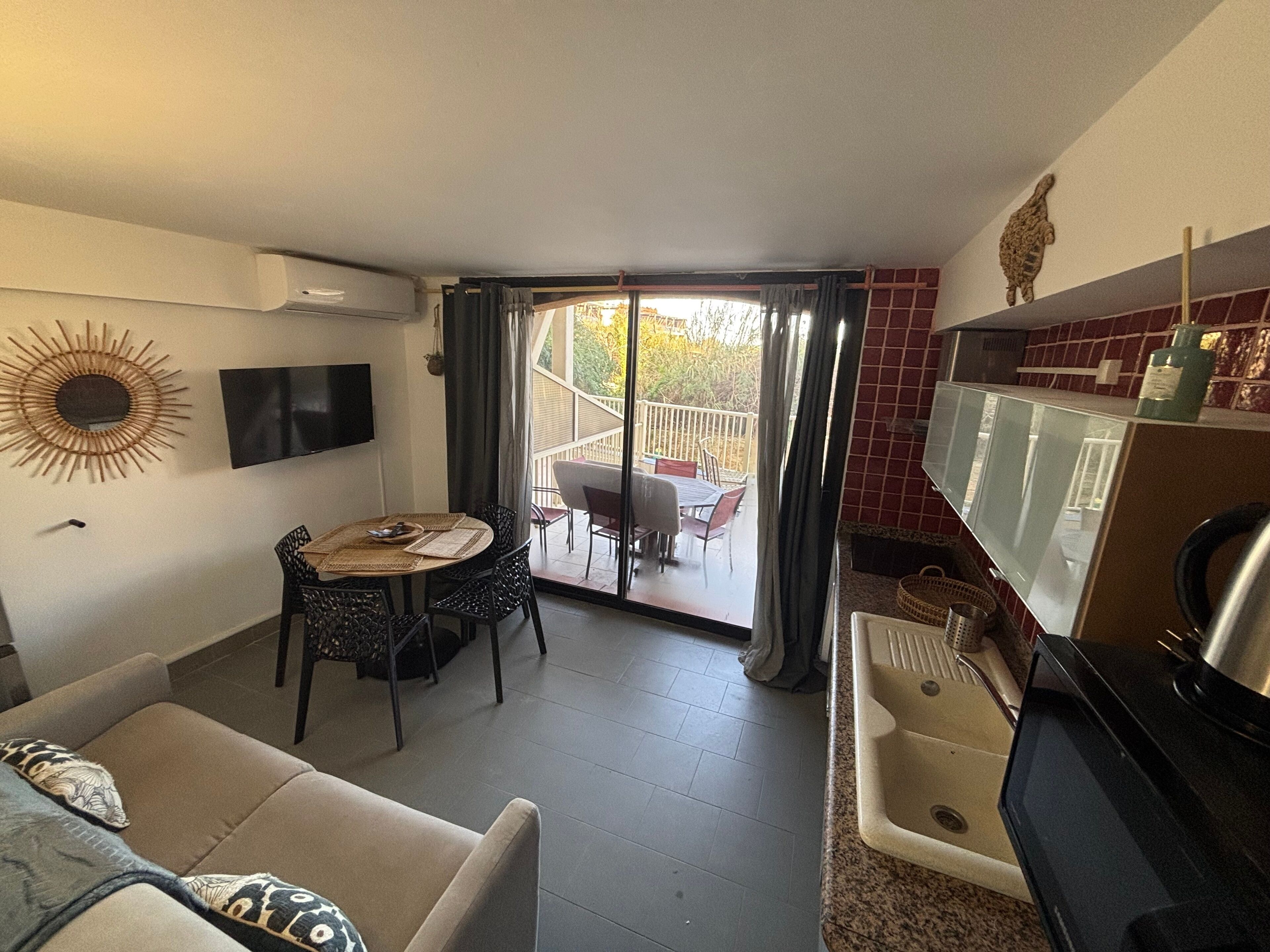 Un espace de vie compact comprenant un coin repas, une kitchenette et un balcon avec vue.
