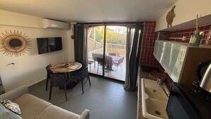 A compact living space with a dining area, kitchenette, and a balcony with a view. - L'Isula - Front de mer -  Appt pour 5 climatisé avec piscine (L'Île-Rousse)