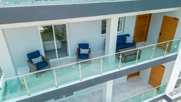 A modern apartment with a balcony, glass railings, and blue furniture.