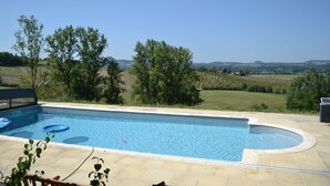 A rectangular swimming pool with a curved edge, surrounded by a tiled deck.