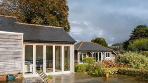 A wooden house with a patio, a bench, and a garden area. - Charming Cottage for 10 in Heart of South Downs (Chichester)