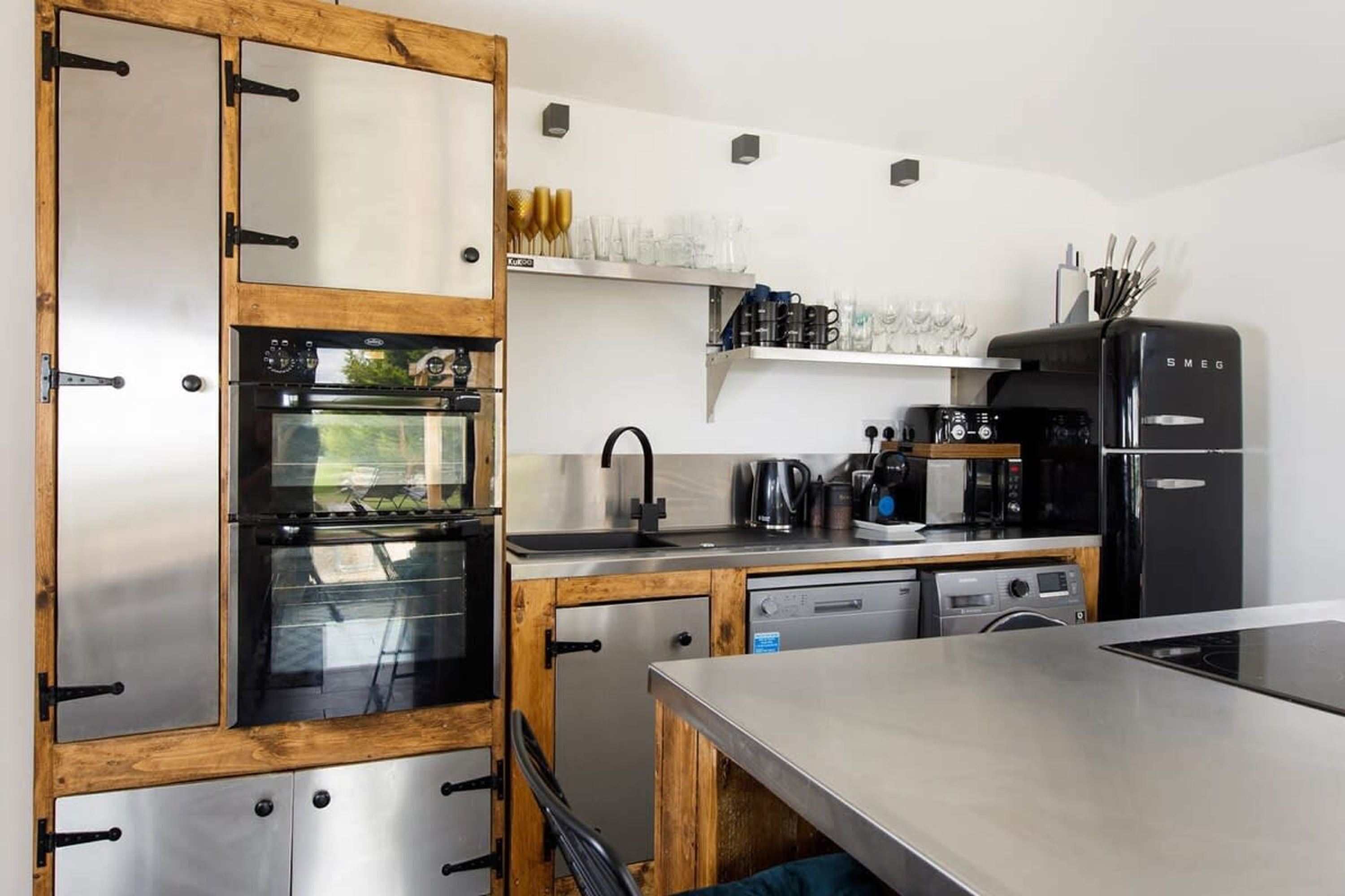 A modern kitchen with stainless steel appliances, wooden cabinets, and a built-in oven.