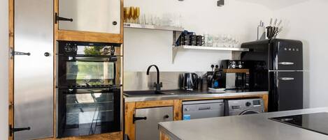 A modern kitchen with stainless steel appliances, wooden cabinets, and a built-in oven.