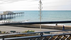 A coastal promenade with a distinctive spiral tower, a pier, and a building with a flat roof.