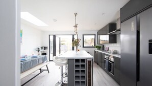 A modern kitchen with a central island, stainless steel appliances, and a view of the outdoors. - Seaside Serenity 3-bed Deck Garden Near Shore (Chichester)