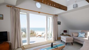 Un salon spacieux doté d’une grande porte-fenêtre coulissante donnant sur un balcon, d’une table basse en bois, d’un canapé et d’un téléviseur.