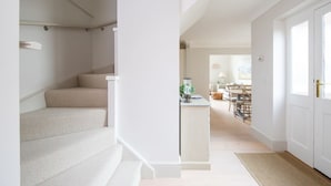 A staircase leading to a living area with a dining table and chairs, a lamp, and a small side table. - Superior House for 6 Near Beach w Parking Garden (Chichester)