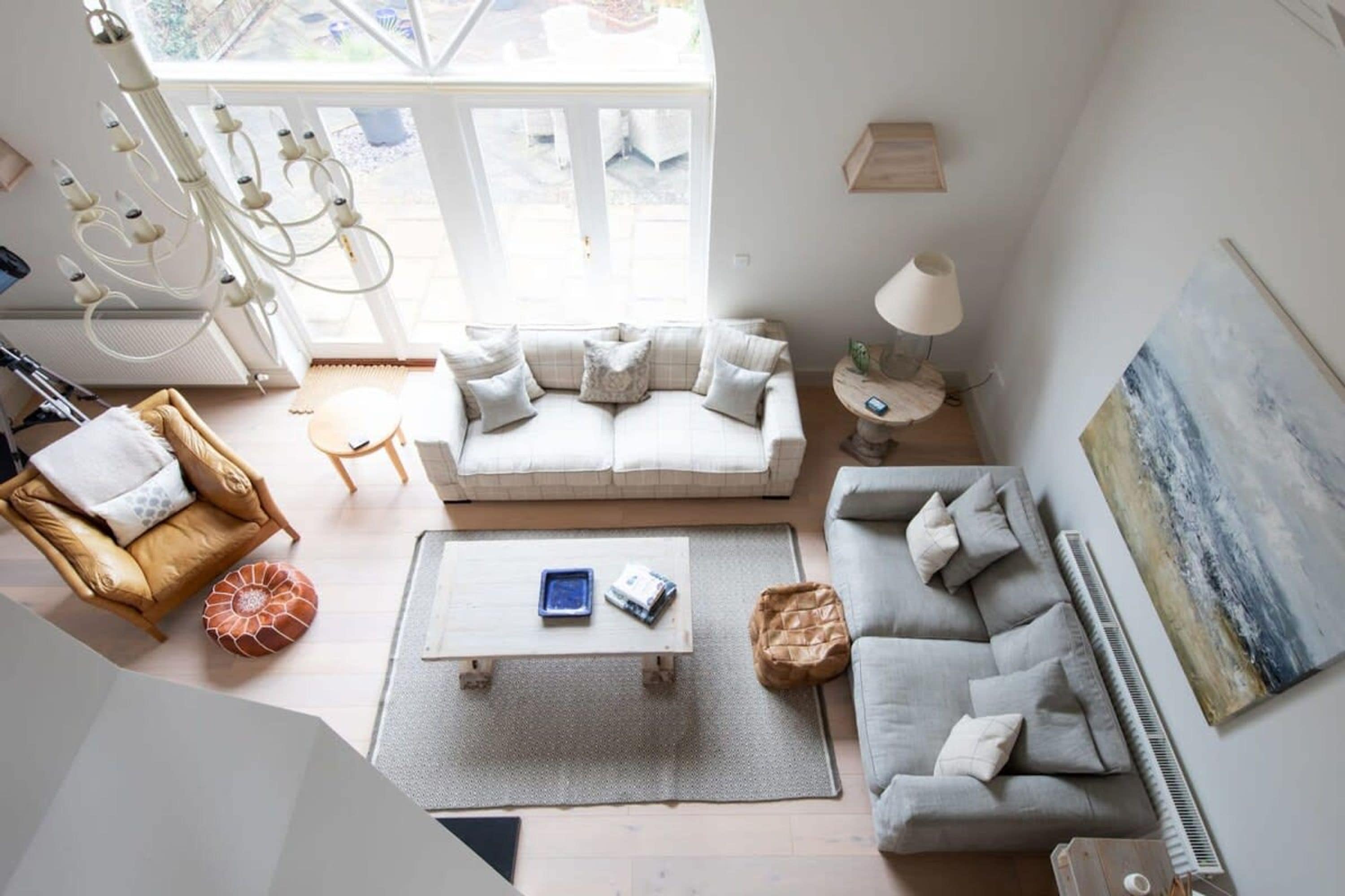 A spacious living room with a large window, a chandelier, a sofa, a coffee table, and a painting on the wall.
