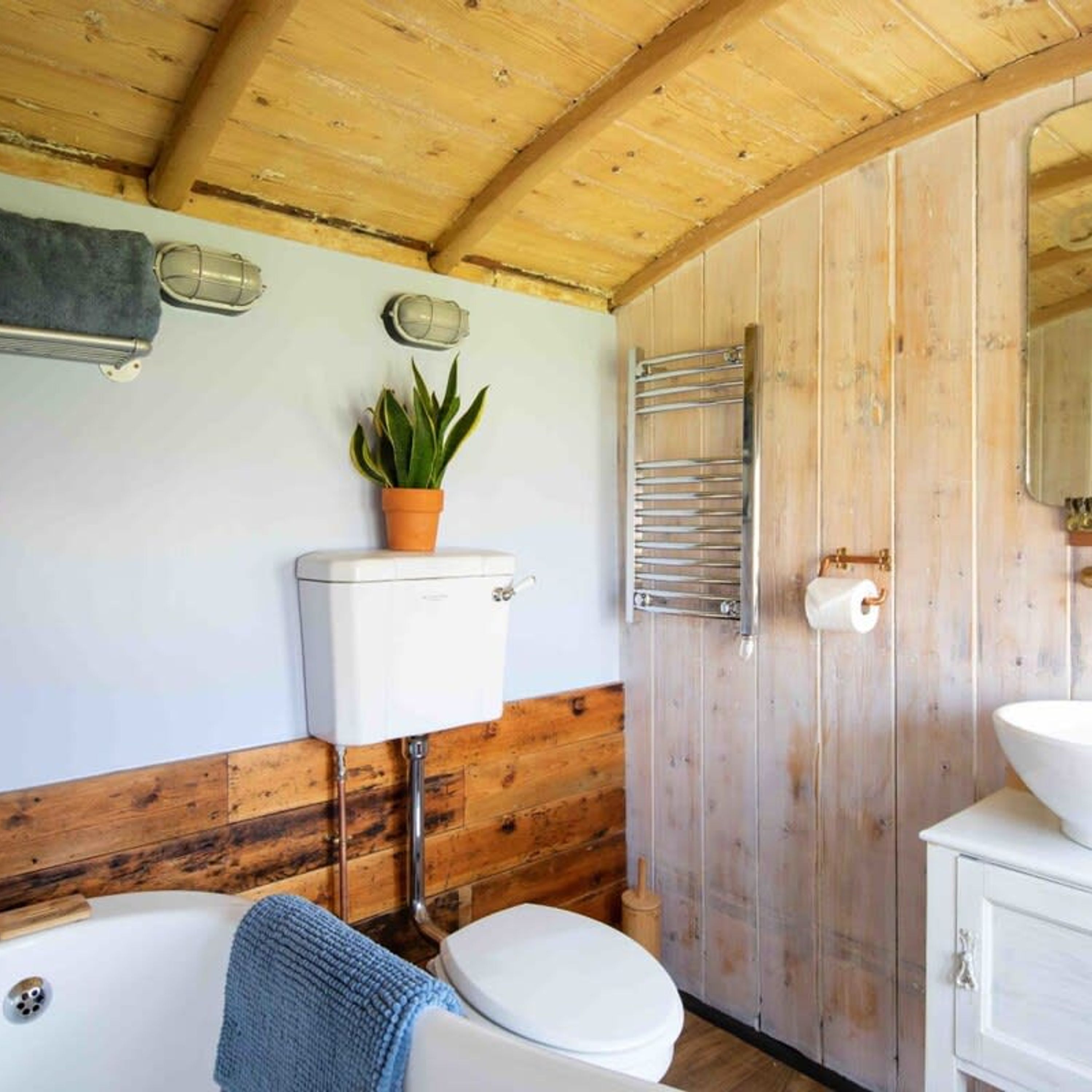 A wooden cabin bathroom with a toilet, sink, and bathtub.