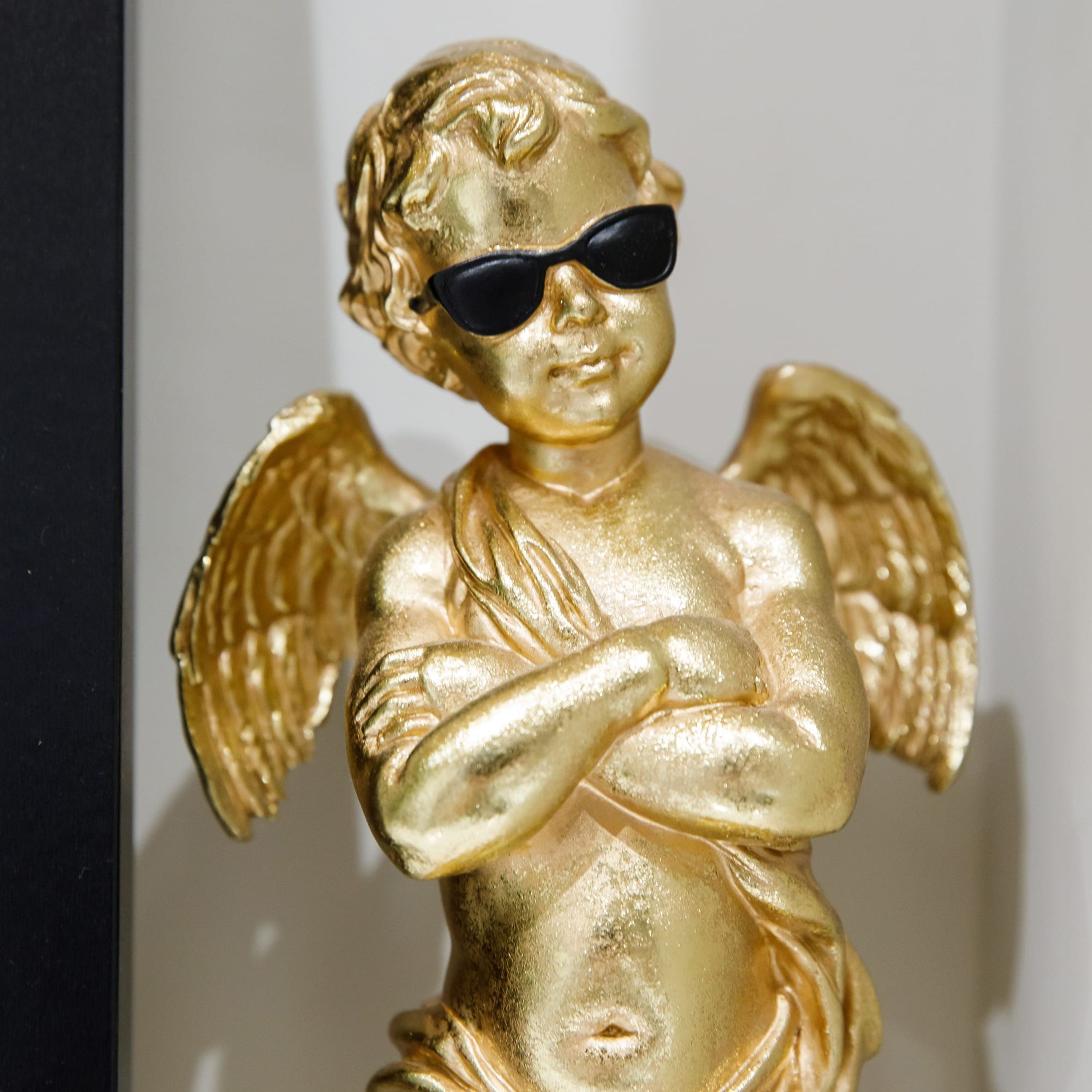 Estátua dourada de anjo com asas e óculos de sol.