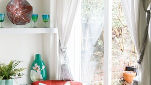 A cozy armchair with a colorful cushion, a potted plant, and a decorative starfish on a shelf. - Beautiful Georgian Home in the Heart of Chichester (Chichester)