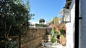 A garden with a table and chairs, a lantern, and a stone wall. - Beautiful Georgian Home in the Heart of Chichester (Chichester)