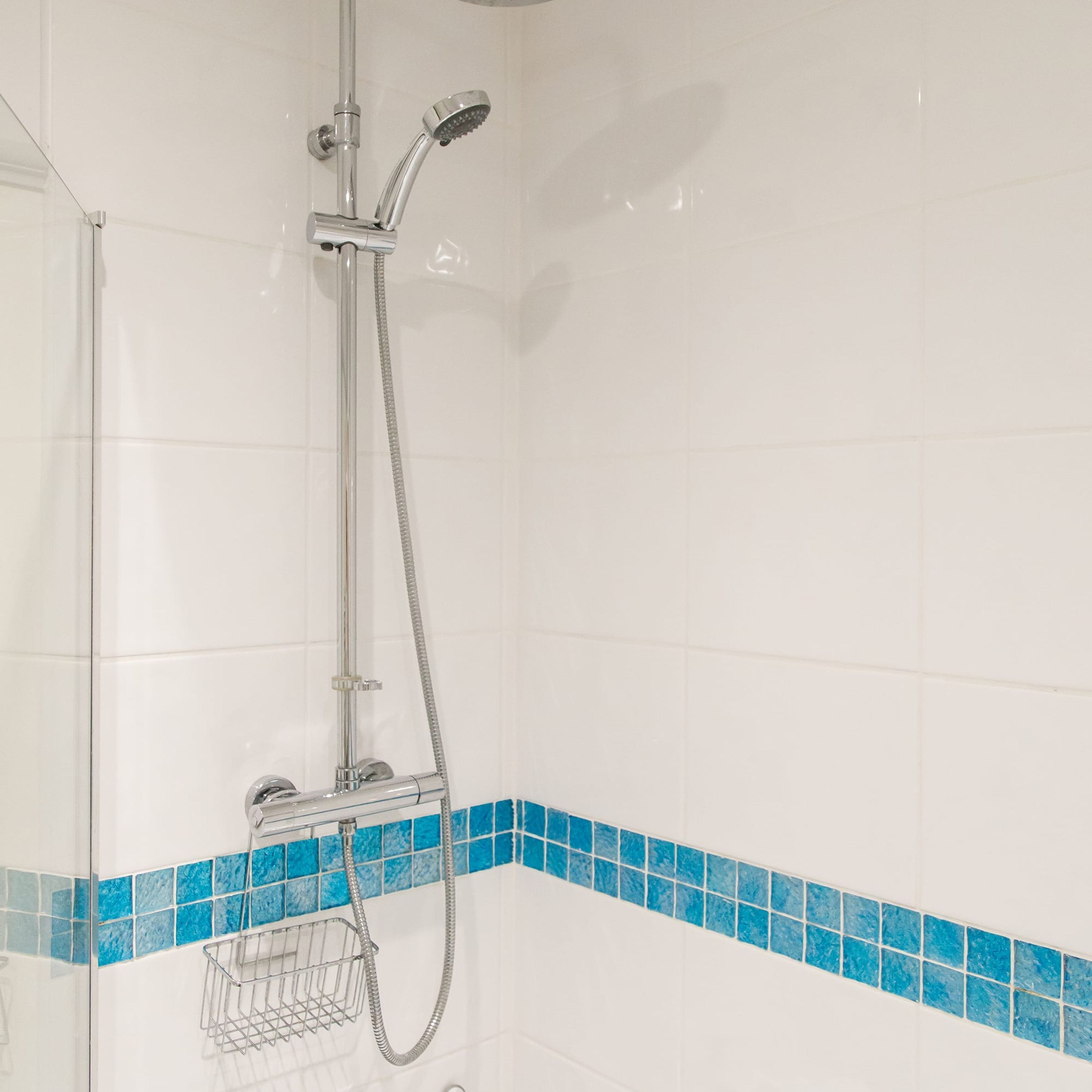 A shower with a handheld showerhead and a wall-mounted faucet.