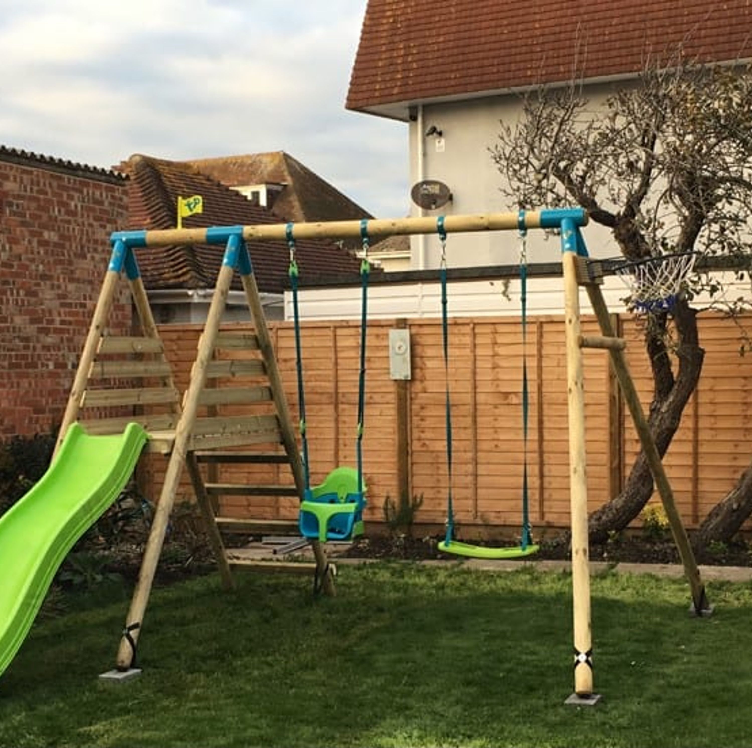 A backyard with a swing set, a slide, and a basketball hoop.