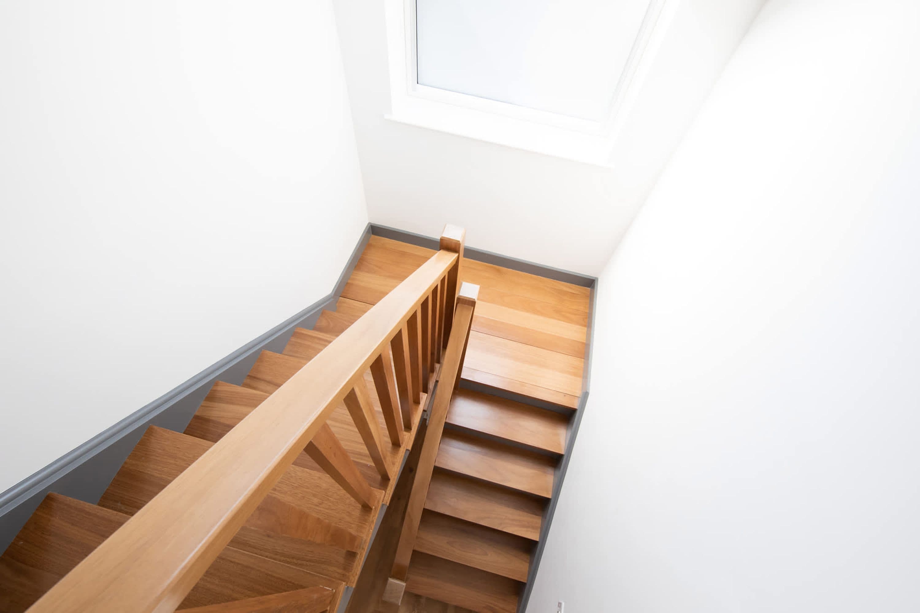 Un escalier en bois, doté d’une rampe, mène à un palier.