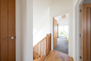 A hallway with wooden doors and a staircase leading to a room with a view.