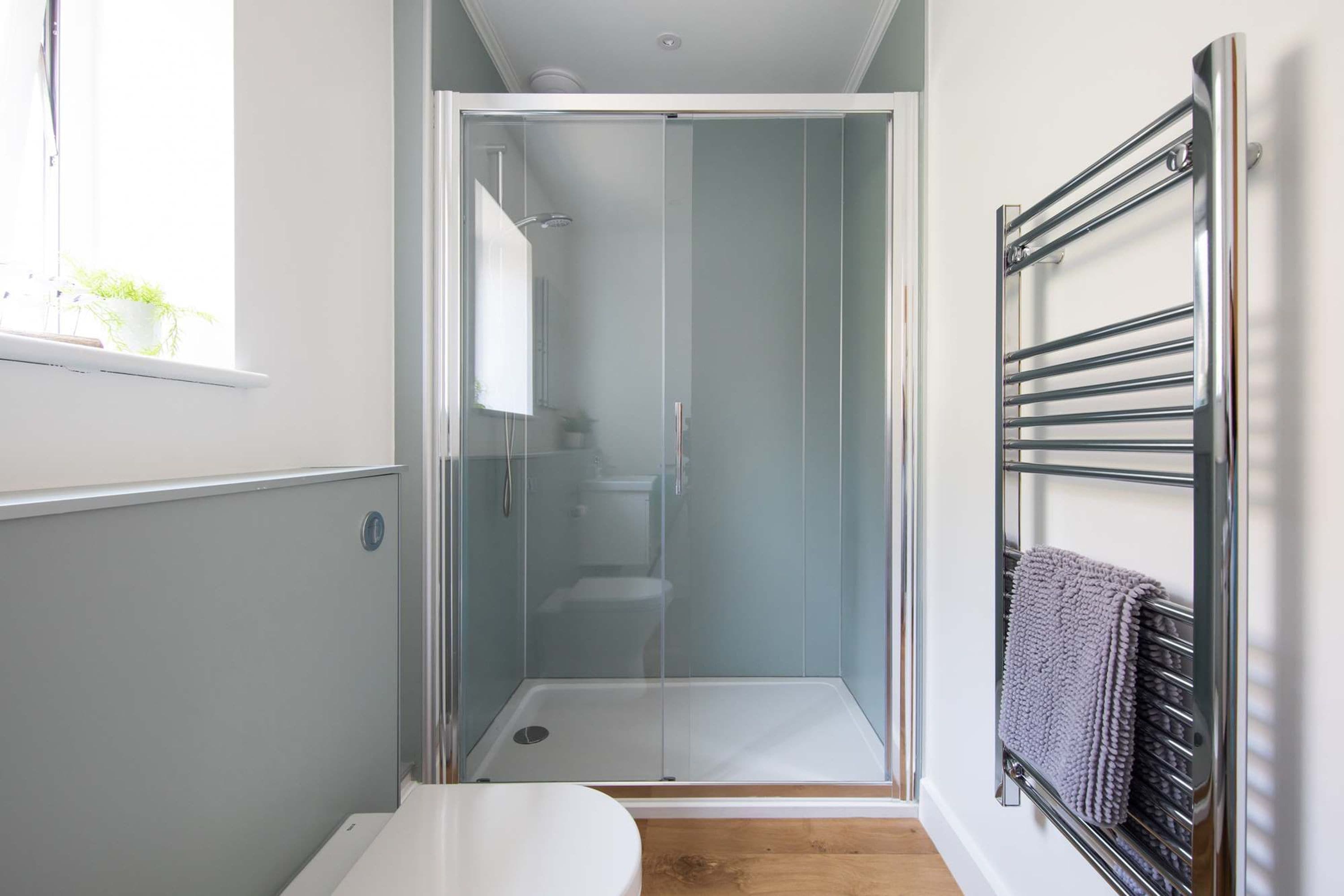 A bathroom with a glass-enclosed shower, a white toilet, and a towel rack.