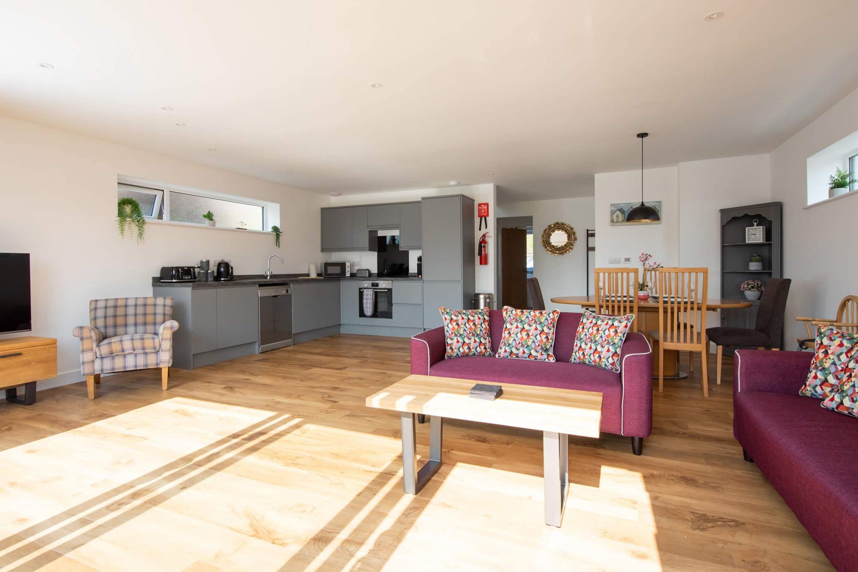 A modern living room with a sofa, a coffee table, and a dining area with chairs and a table.