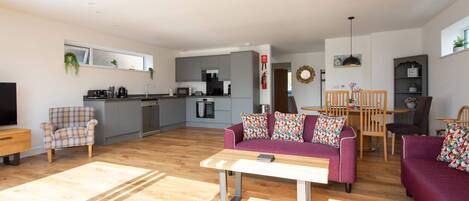 A modern living room with a sofa, a coffee table, and a dining area with chairs and a table.