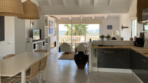 A modern kitchen with a large island, white cabinetry, and a view of the outdoors.