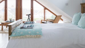 A bedroom with a sloped ceiling, a bed with a white mattress and teal bedding, a fluffy white rug, and a telescope on a desk. - Tranquil Family Retreat 5 min to Beach Garden (Chichester)