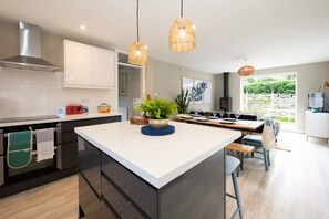 Enjoy cooking in this well-equipped kitchen with a central island, stainless steel appliances, and a large window offering a view of the surrounding greenery.