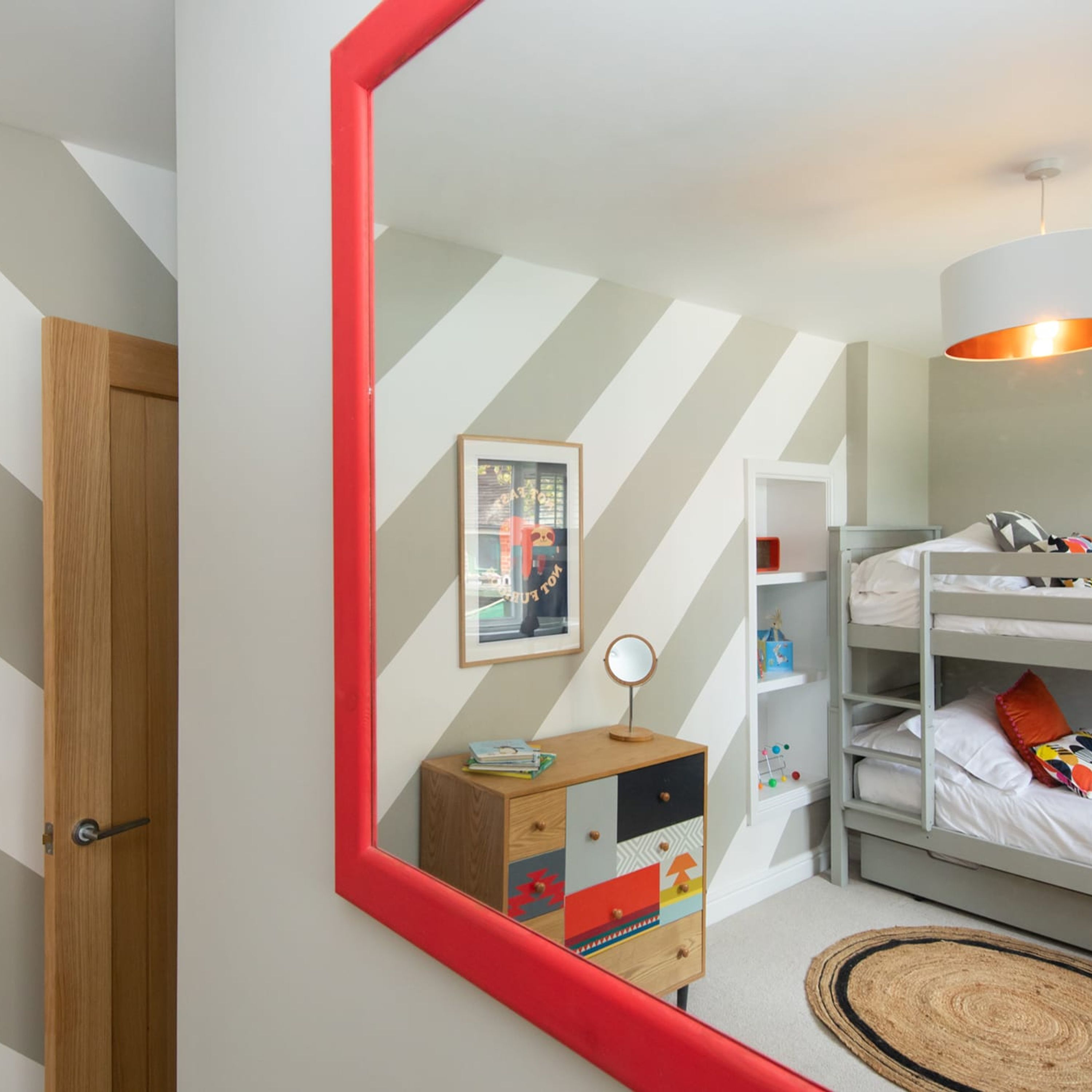 A child's bedroom with a bunk bed, a dresser with a mirror, and a framed picture on the wall.