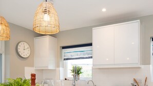 A modern kitchen with white cabinetry, a wooden island, and a large window. - Bosham 3 BR Beach House With Garden Playhouse (Chichester)